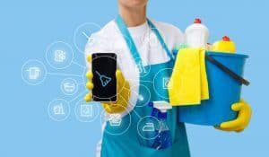 Man holding cleaning supplies and phone with cleaning app.